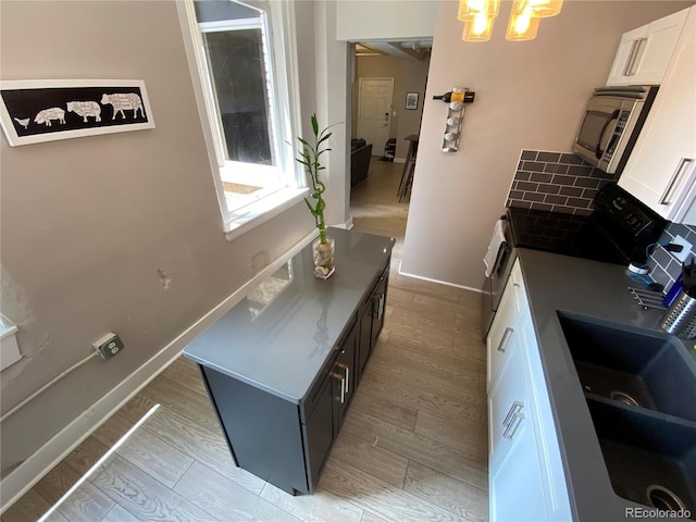 444 17th St Unit 508, Denver, CO 80202 - kitchen with stainless steel microwave, white cabinets, light wood-style floors, a chandelier, and tasteful backsplash