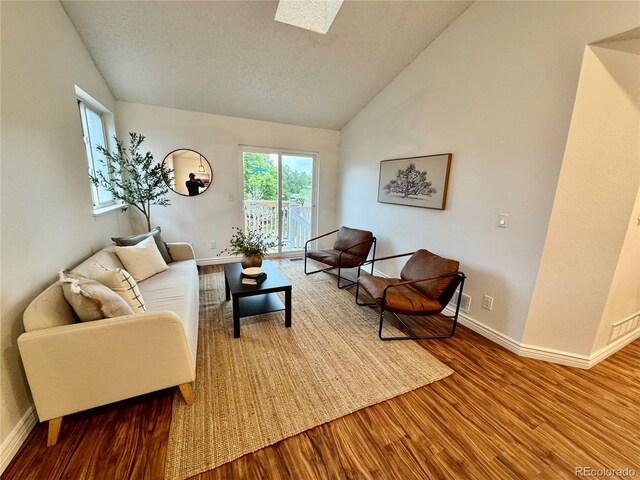 4036 S Himalaya Cir, Aurora, CO 80013 - living area with wood finished floors, vaulted ceiling, baseboards, a textured ceiling, and a skylight