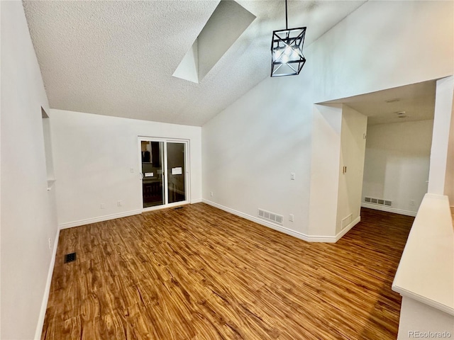 4036 S Himalaya Cir, Aurora, CO 80013 - unfurnished living room with a skylight, wood finished floors, baseboards, high vaulted ceiling, and a textured ceiling
