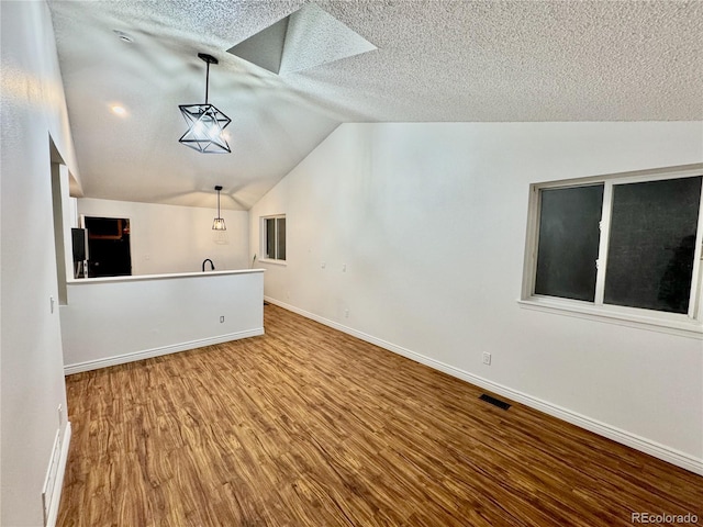4036 S Himalaya Cir, Aurora, CO 80013 - unfurnished living room featuring lofted ceiling, wood finished floors, a textured ceiling, and baseboards