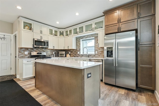 3165 W 63rd Ave, Denver, CO 80221 - kitchen featuring tasteful backsplash, appliances with stainless steel finishes, light wood finished floors, and a kitchen island
