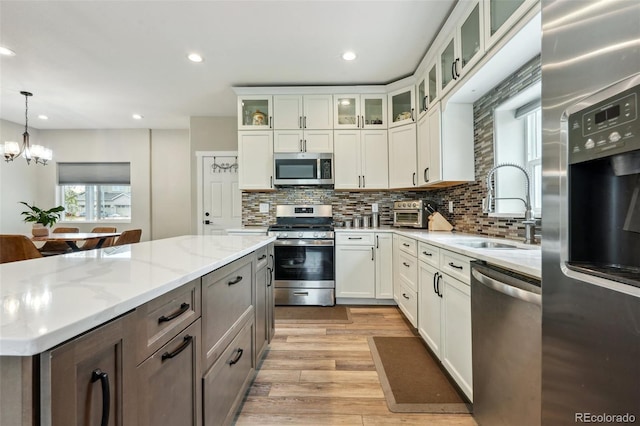 3165 W 63rd Ave, Denver, CO 80221 - kitchen featuring a sink, backsplash, appliances with stainless steel finishes, and light wood-style floors