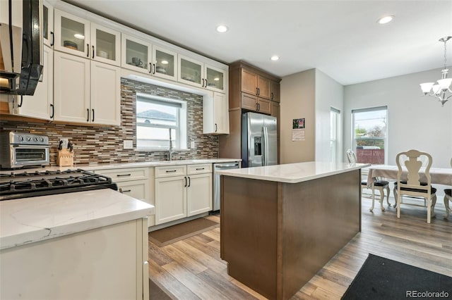 3165 W 63rd Ave, Denver, CO 80221 - kitchen featuring backsplash, a wealth of natural light, appliances with stainless steel finishes, and an inviting chandelier