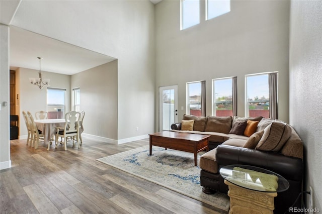 3165 W 63rd Ave, Denver, CO 80221 - living room featuring wood finished floors, an inviting chandelier, a high ceiling, and baseboards