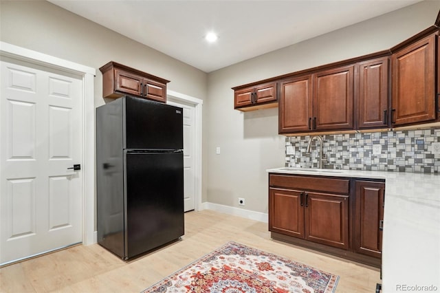 3165 W 63rd Ave, Denver, CO 80221 - kitchen with a sink, light countertops, freestanding refrigerator, light wood-style floors, and backsplash