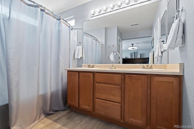 16086 E 97th Pl, Commerce City, CO 80022 - full bathroom featuring wood finished floors, double vanity, a shower with curtain, and a textured wall
