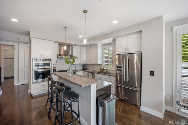 3690 W Byron Pl, Denver, CO 80211 - kitchen with appliances with stainless steel finishes, wall chimney exhaust hood, plenty of natural light, a center island, and recessed lighting