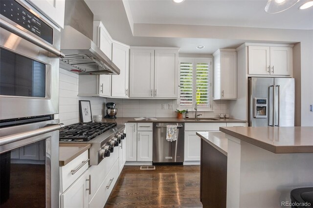 3690 W Byron Pl, Denver, CO 80211 - kitchen with stainless steel appliances, wall chimney exhaust hood, recessed lighting, dark wood finished floors, and backsplash