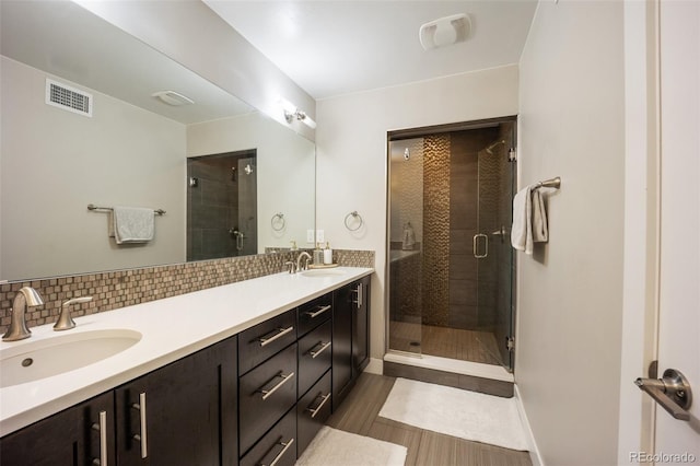 3690 W Byron Pl, Denver, CO 80211 - bathroom with double vanity, a shower stall, tasteful backsplash, and wood finished floors