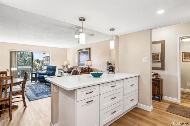 kitchen featuring pendant lighting, light countertops, a ceiling fan, white cabinetry, and light wood-type flooring