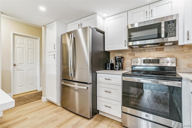 kitchen with stainless steel appliances, light countertops, backsplash, and white cabinetry