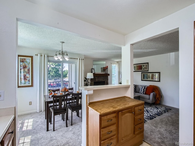 7700 N Depew St Unit 1518, Arvada, CO 80003 - kitchen featuring light colored carpet, a chandelier, a textured ceiling, light countertops, and a stone fireplace