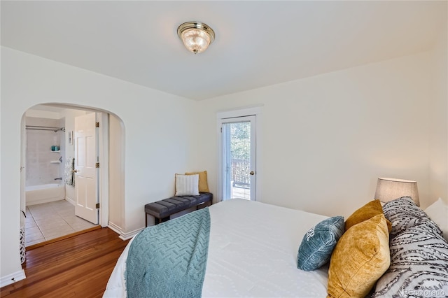 2854 Eliot St, Denver, CO 80211 - bedroom featuring baseboards, connected bathroom, wood finished floors, arched walkways, and access to exterior