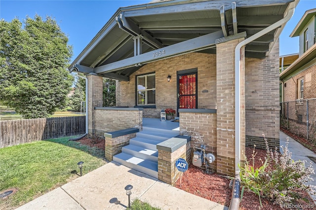 view of exterior entry with a porch and a lawn