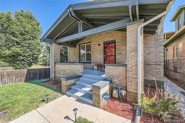 2854 Eliot St, Denver, CO 80211 - view of exterior entry featuring a porch, fence, brick siding, and a lawn