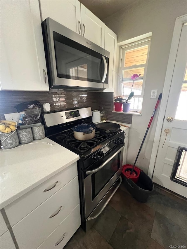 2655 Pontiac St, Denver, CO 80207 - kitchen featuring appliances with stainless steel finishes, tasteful backsplash, light countertops, and white cabinetry