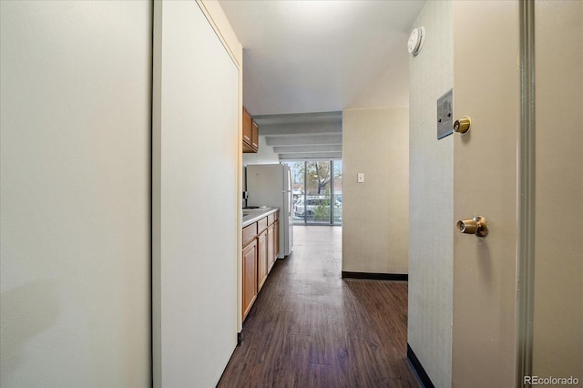 corridor with dark wood-style flooring and baseboards