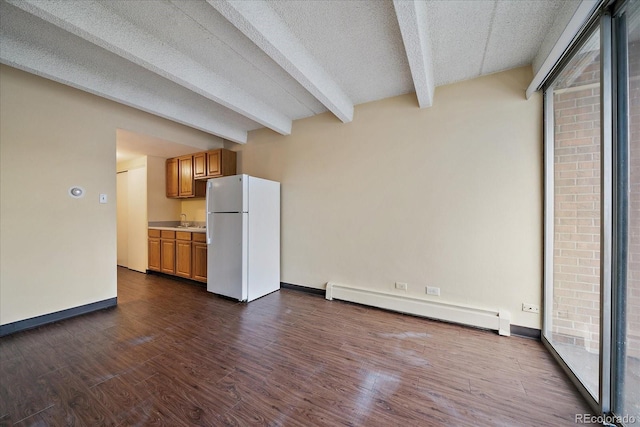 unfurnished living room with a baseboard heating unit, beam ceiling, dark wood-type flooring, baseboards, and a sink
