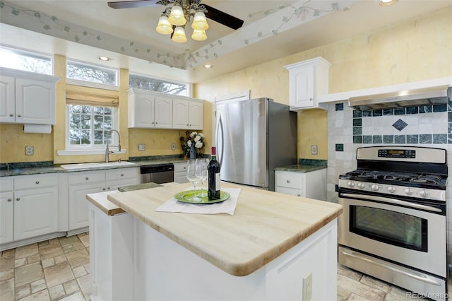31 N Algonquian St, Aurora, CO 80018 - kitchen with stainless steel appliances, a sink, stone tile flooring, white cabinetry, and tasteful backsplash
