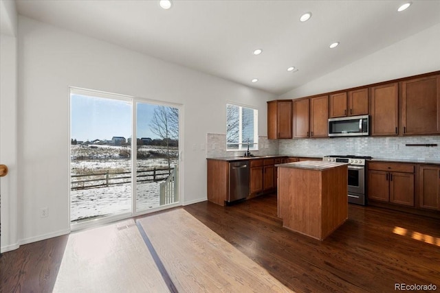 kitchen featuring a center island, sink, stainless steel appliances, dark hardwood / wood-style floors, and vaulted ceiling