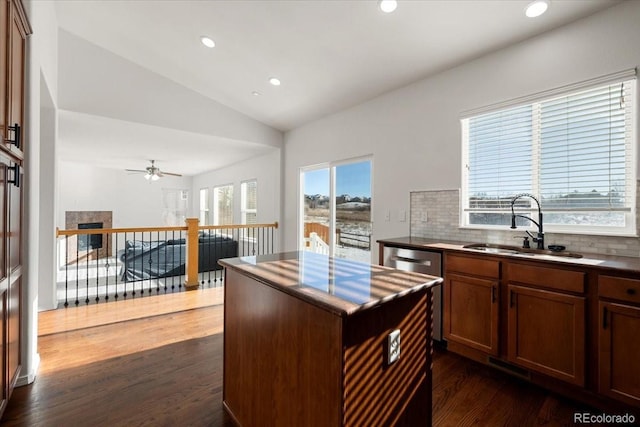 kitchen with decorative backsplash, ceiling fan, dark wood-type flooring, sink, and a kitchen island