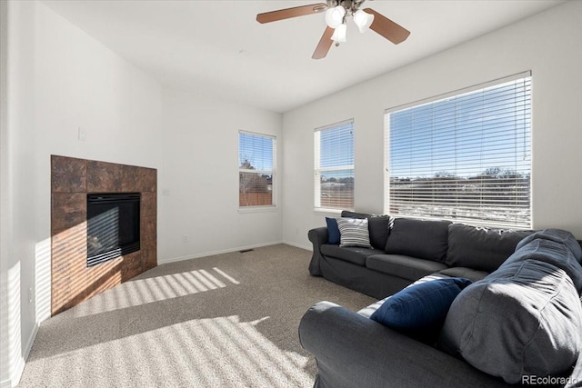 carpeted living room featuring a tile fireplace and ceiling fan