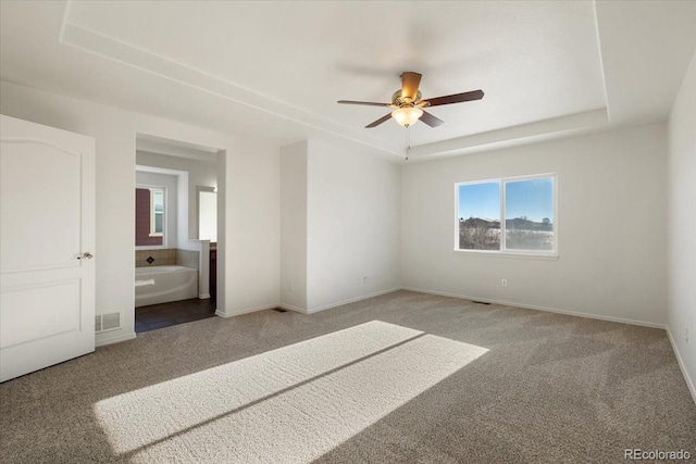 interior space featuring carpet floors, ensuite bath, a raised ceiling, and ceiling fan