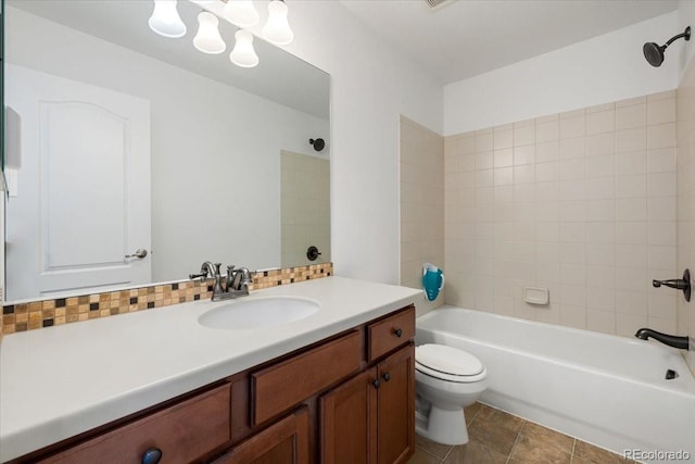 full bathroom featuring tiled shower / bath combo, toilet, vanity, and tasteful backsplash