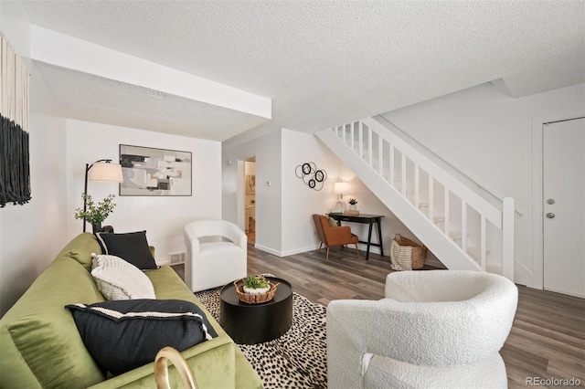 living area with stairway, a textured ceiling, and wood finished floors