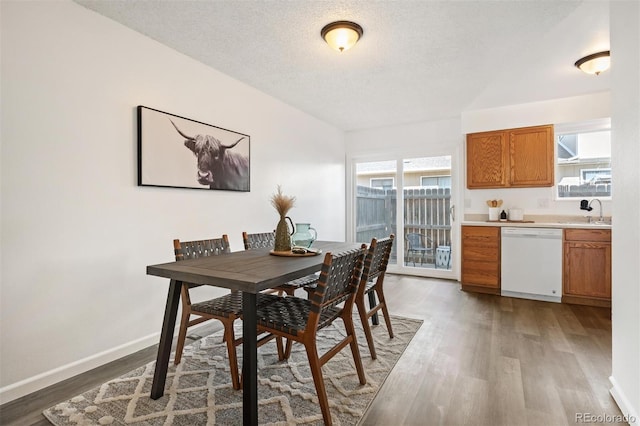 dining space with baseboards, light wood finished floors, and a textured ceiling