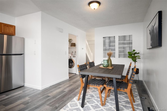 dining space featuring baseboards, a textured ceiling, washer / dryer, and wood finished floors