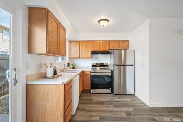 kitchen featuring dark wood-style floors, a sink, light countertops, under cabinet range hood, and appliances with stainless steel finishes