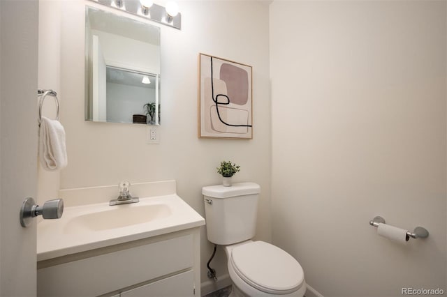 half bathroom featuring vanity, toilet, and baseboards