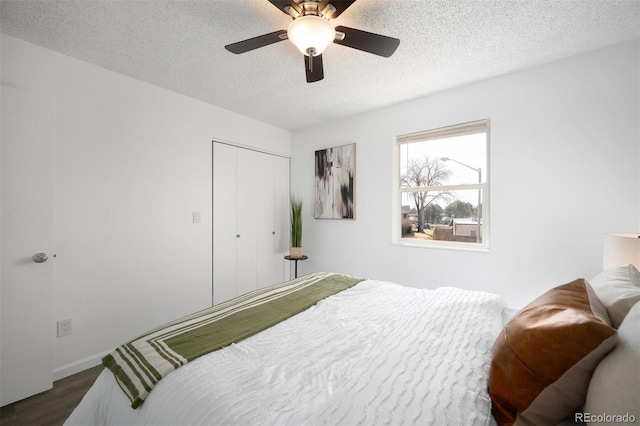 bedroom featuring ceiling fan, dark wood-style flooring, a closet, and a textured ceiling