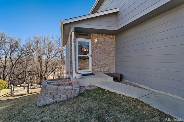 entrance to property featuring a yard and brick siding