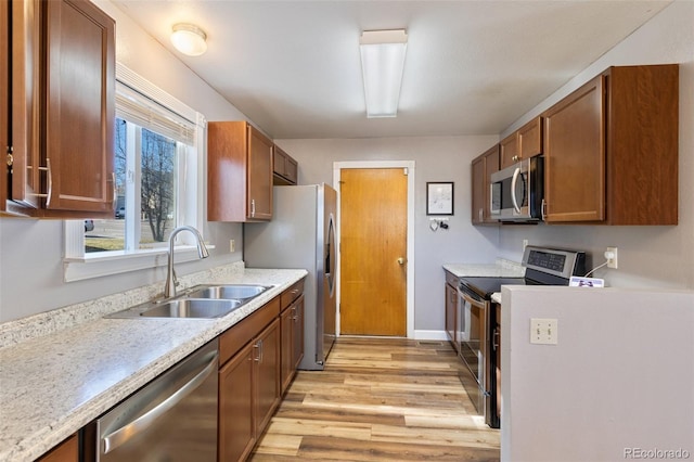 kitchen featuring a sink, light wood-type flooring, appliances with stainless steel finishes, and light countertops