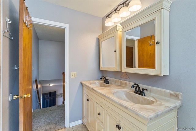 bathroom featuring double vanity, baseboards, tile patterned floors, and a sink