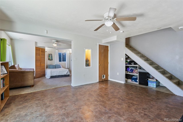 unfurnished living room with stairway, baseboards, and a ceiling fan