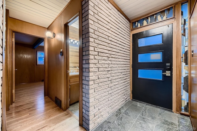 foyer entrance featuring wooden walls and wooden ceiling