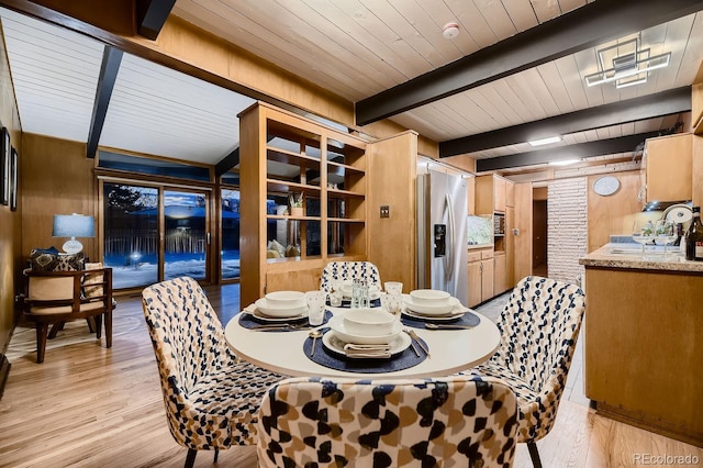 dining room with light wood-type flooring, wooden walls, wooden ceiling, and beam ceiling