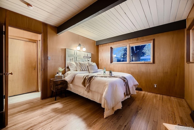 bedroom featuring beamed ceiling, wood ceiling, light wood-type flooring, and wood walls