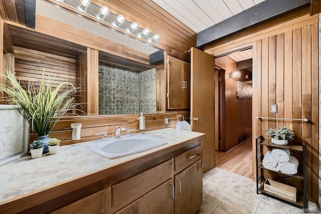 bathroom featuring beamed ceiling, vanity, and wooden walls