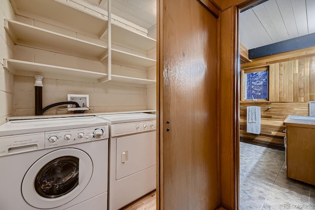 washroom featuring washing machine and clothes dryer and wooden walls