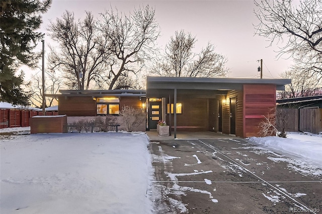 snow covered rear of property featuring a carport