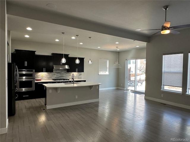 kitchen featuring a kitchen bar, light countertops, freestanding refrigerator, dark cabinetry, and a sink