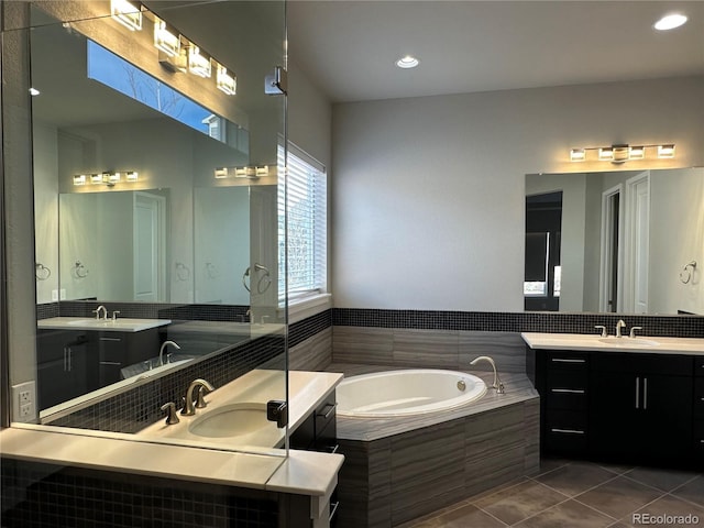 full bathroom featuring two vanities, tile patterned floors, a bath, and a sink