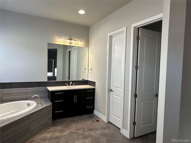 bathroom featuring tile patterned flooring, a bath, vanity, and baseboards