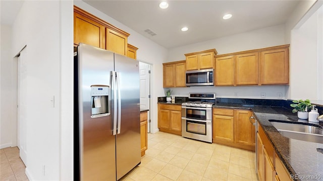 kitchen with recessed lighting, stainless steel appliances, visible vents, brown cabinets, and dark stone countertops