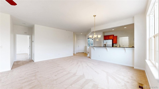 unfurnished living room featuring visible vents, light carpet, and baseboards