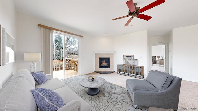 carpeted living area featuring a tile fireplace, a ceiling fan, and baseboards